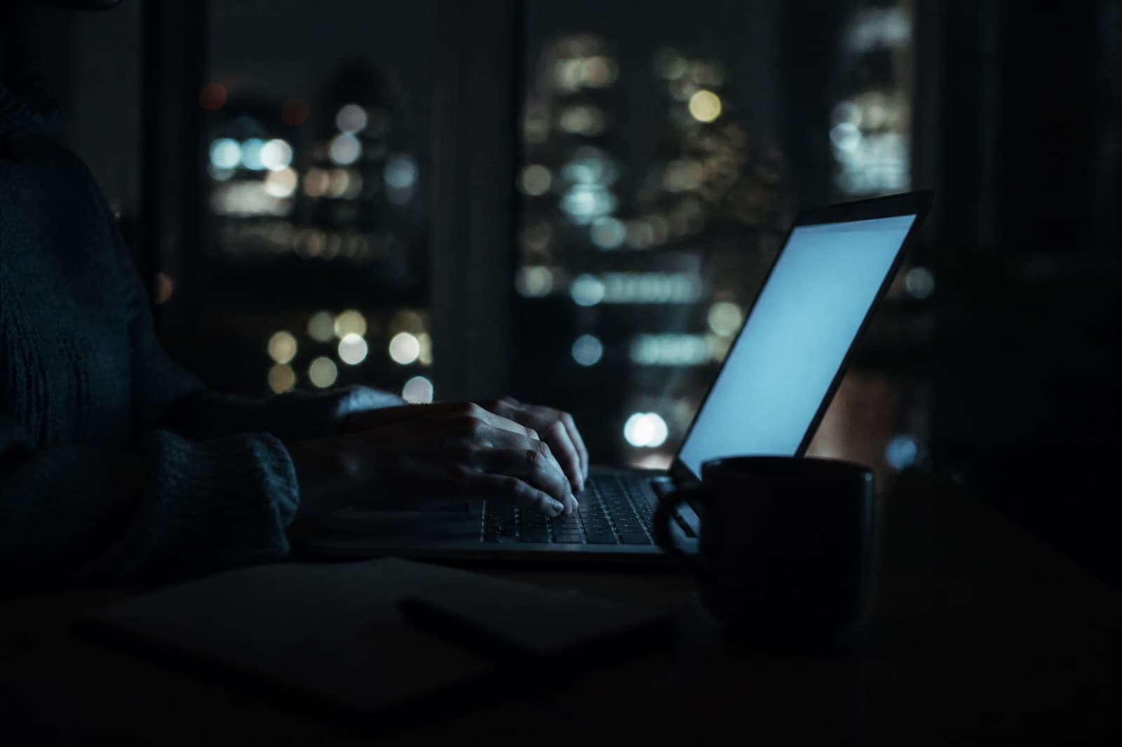 Hands on a laptop at night, lit only by the screen