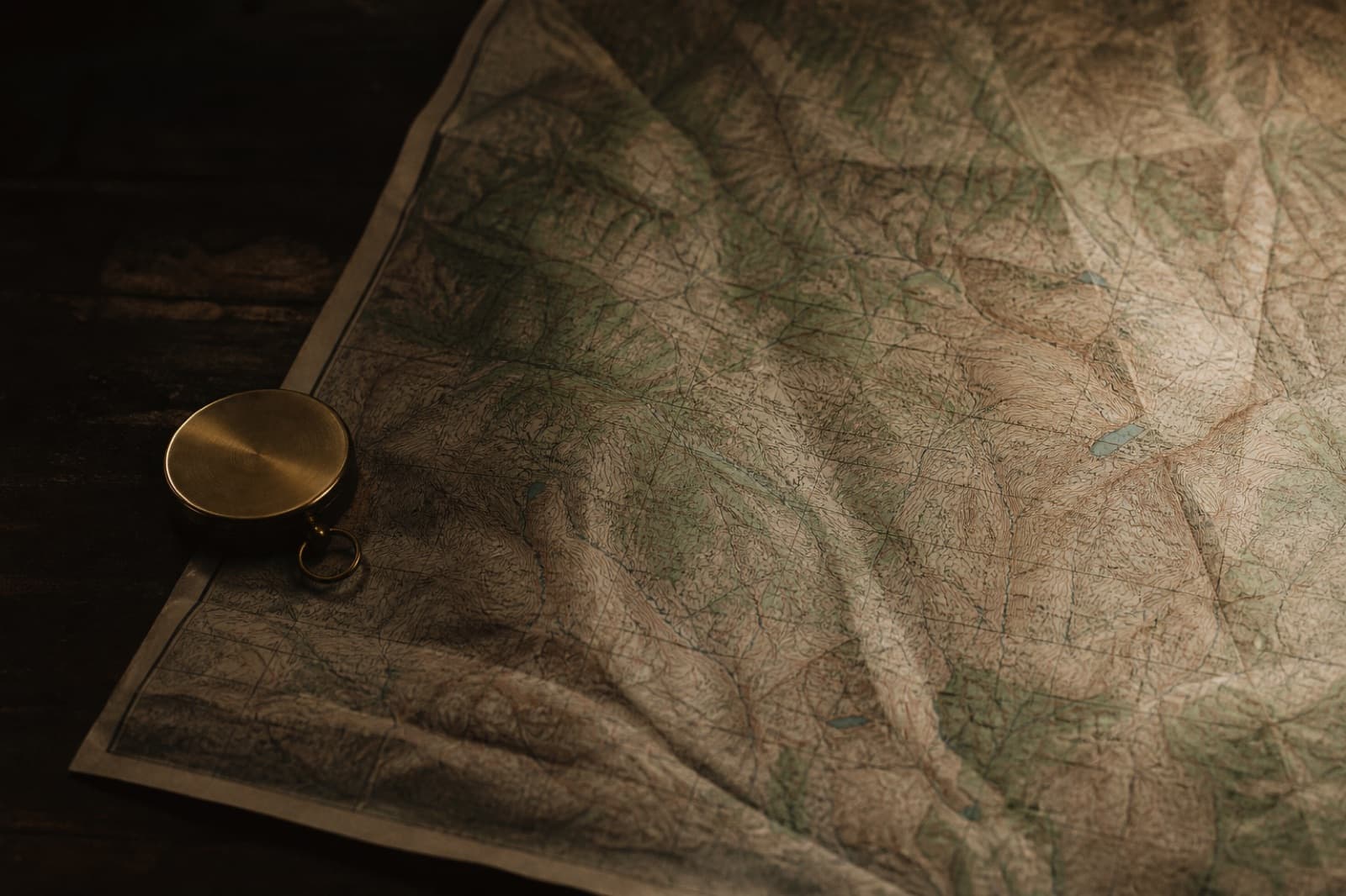 An unlabeled topographic map and a closed brass compass