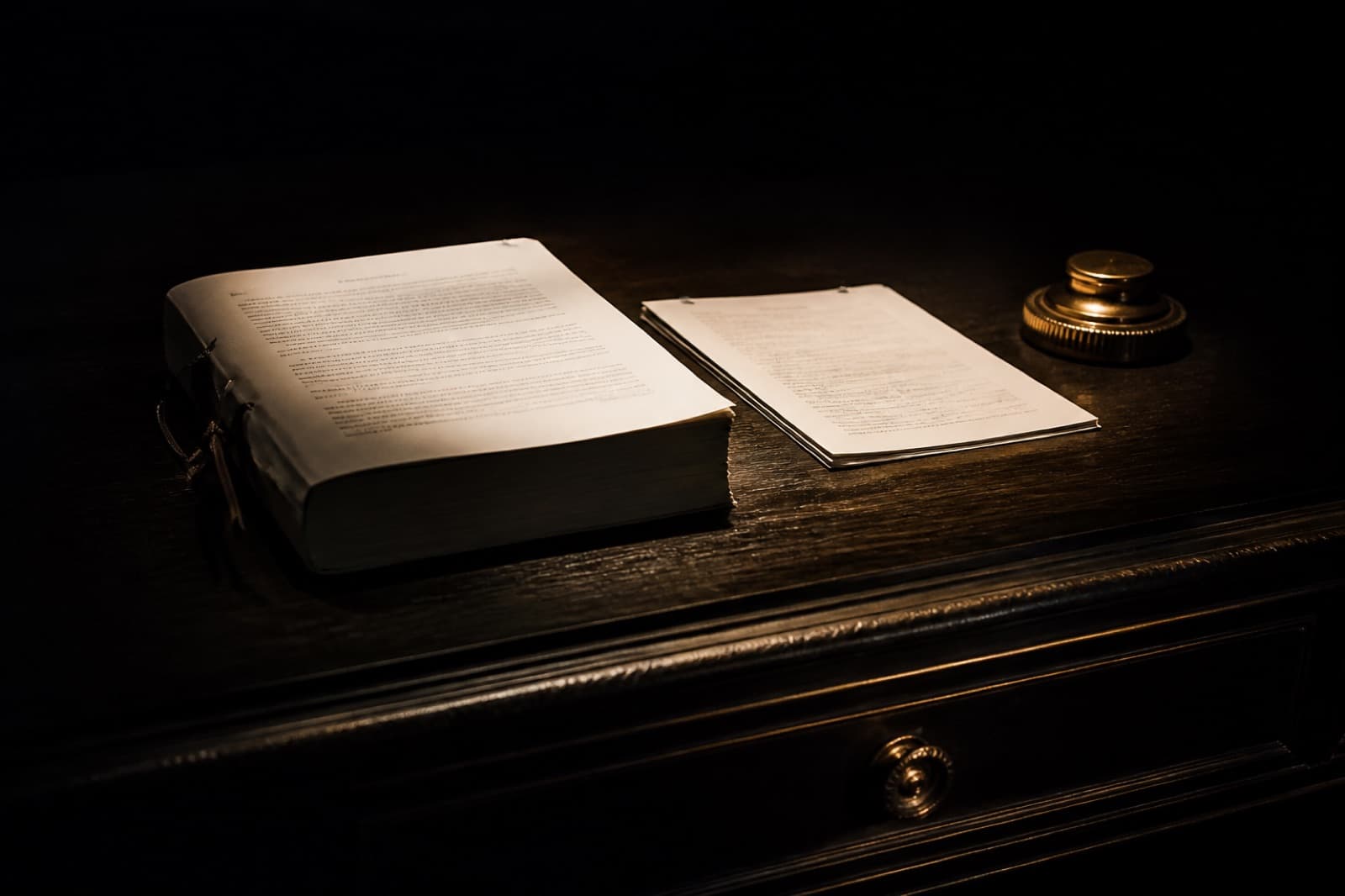 A legal document and a thinner stapled packet on a black desk